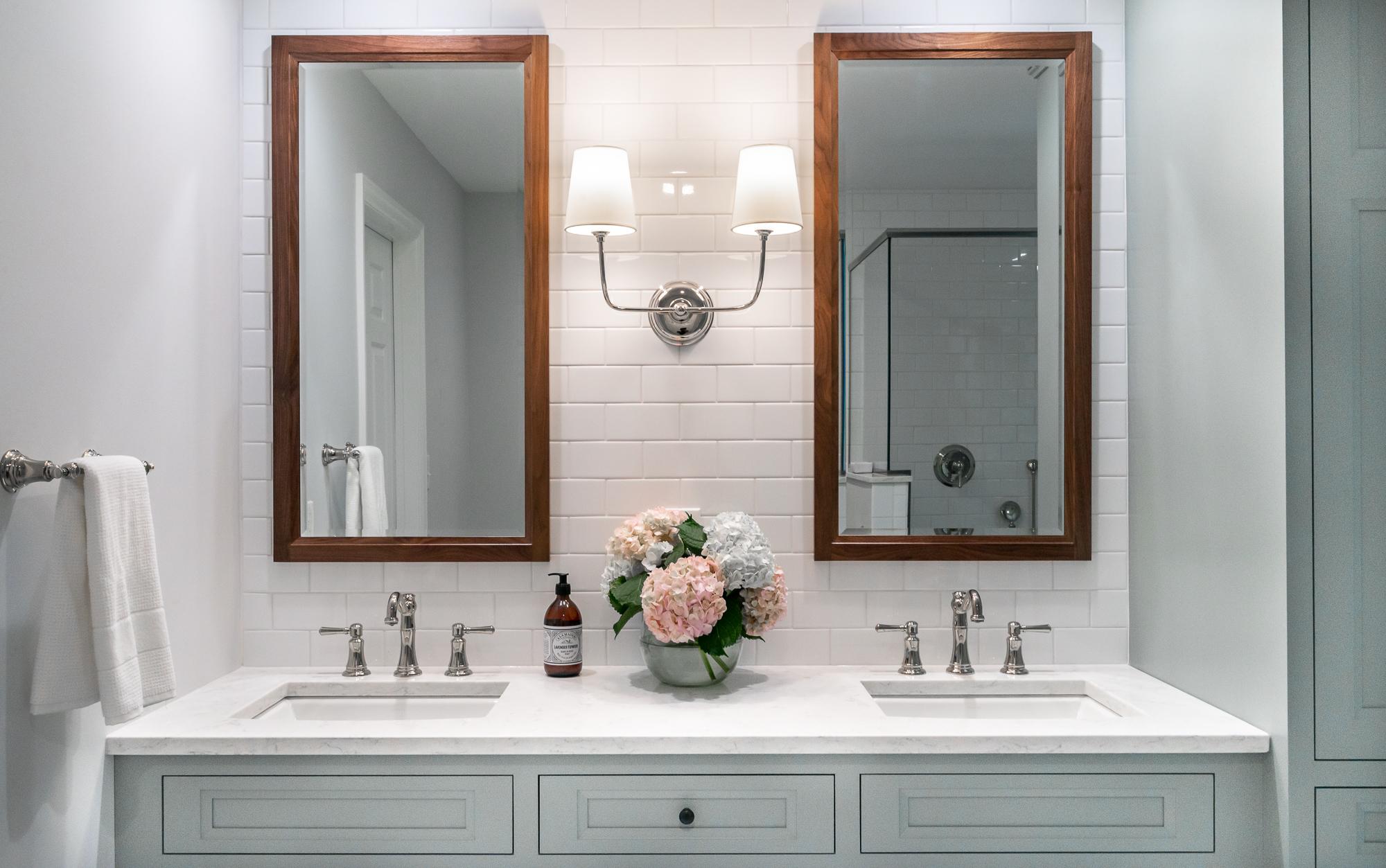 Bathroom with white tile, teal cabinets, and duel mirrors